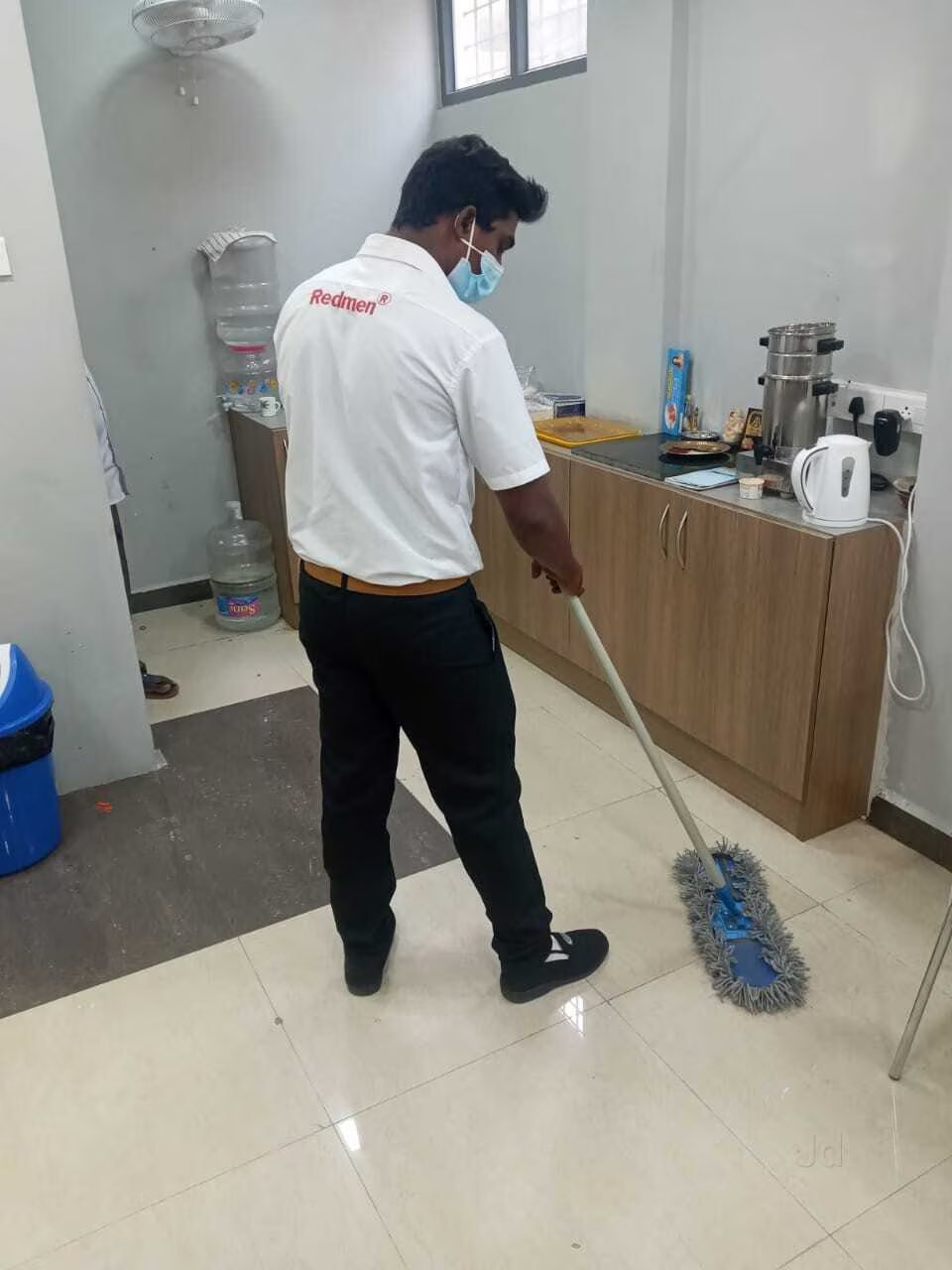 A Kaizeen housekeeping team member mopping an office pantry floor